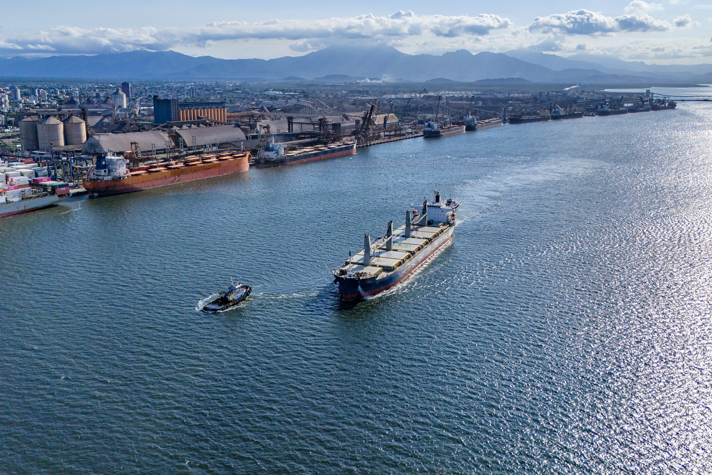 Navio centralizado no mar azul cruz a Baía de Paranaguá enquanto o Porto de Paranaguá opera ao fundo com vários navios atracados #praquemnaopodever
