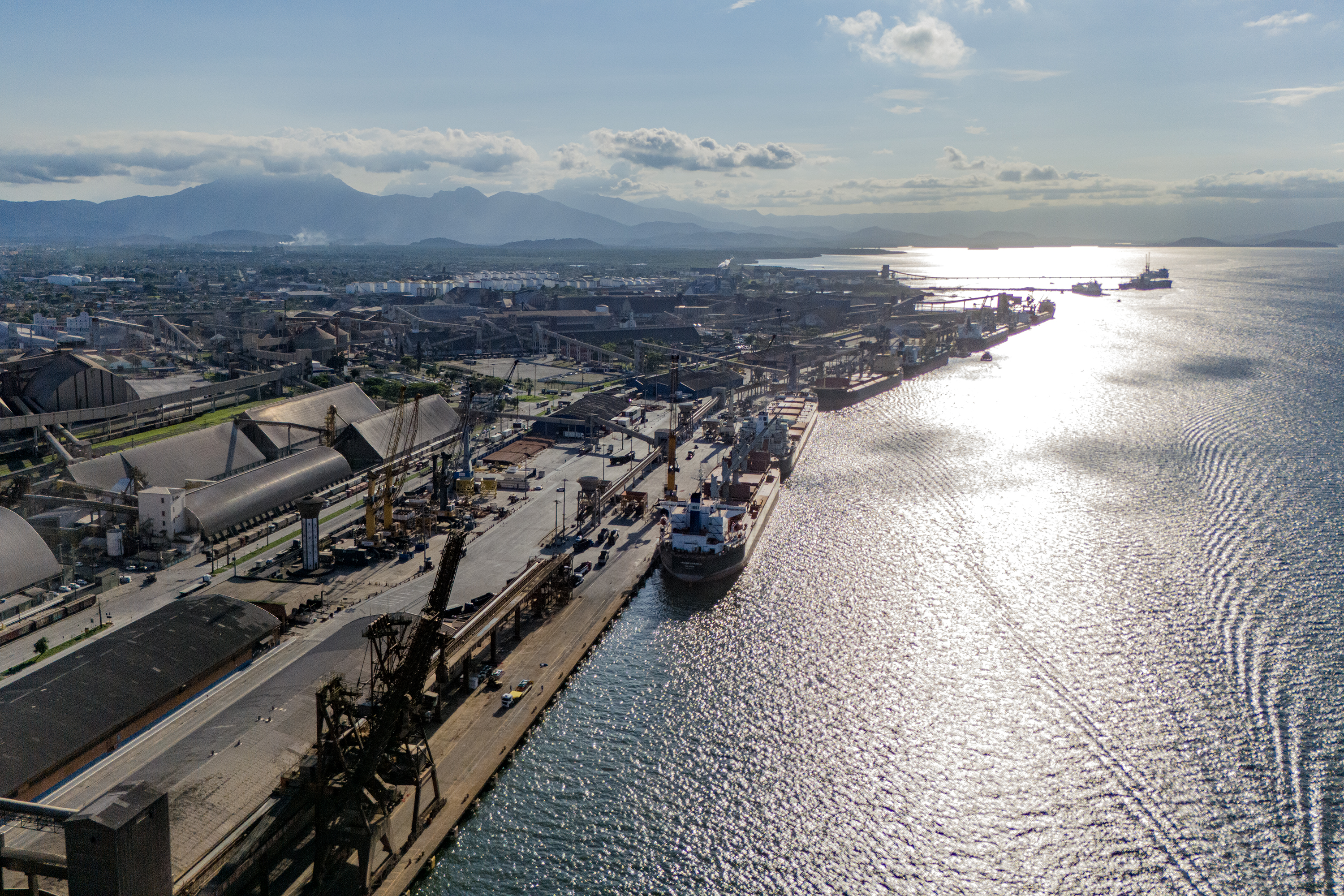 Imagem aérea do Porto de Paranaguá mostrando o cais contra a luz enquanto os navios operam.