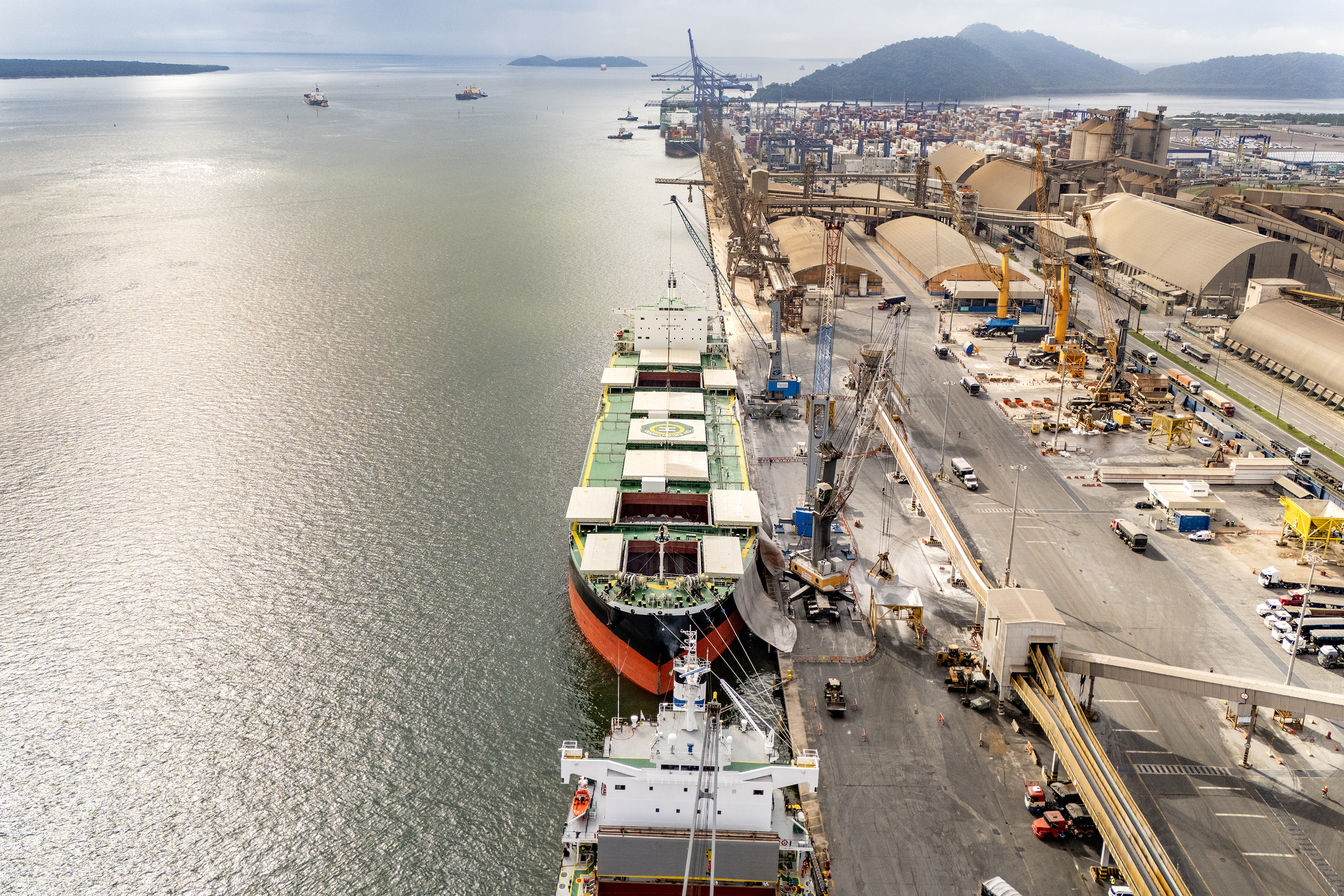 #praquemnaopodever imagem aérea do navio verde com três poroes abertos e operando bags de fertilizantes. Metade da foto é baía de Paranaguá e outra metade é cais do Porto de Paranaguá