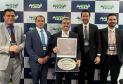 #ParaQuemNaoPodeVer Foto de cinco homens de terno, posando para uma foto em frente a um painel com o logo “ANDAV LATAM”. Eles estão sorrindo e segurando um quadro e um troféu, sugerindo que receberam algum tipo de prêmio ou reconhecimento. O ambiente parece ser um evento corporativo ou uma premiação.