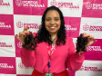 #praquemnaopodever foto mostra mulher negra de camisa rosa segurando uma mecha de cabelo de cada lado e sorrindo em frente de uma parede com os dizeres Portos do Paraná em rosa.