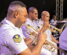 #praquemnaopodever musicistas de branco sentados em cadeiras de madeira aparecem de lado tocando concentrados os instrumentos.