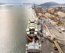 #praquemnaopodever imagem aérea do navio verde com três poroes abertos e operando bags de fertilizantes. Metade da foto é baía de Paranaguá e outra metade é cais do Porto de Paranaguá