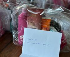 #praquemnaopodever um bilhete branco está aberto a frente de várias bolsas transparentes com produtos de higiene e cuidados pessoais em cima de uma mesa