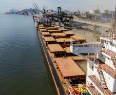 #praquemnaopodever foto aérea do cais do Porto de Paranaguá, na ponta direita está o navio graneleiro com todos os porões carregados de soja. O céu está azul e o cais está lotado de embarcações.