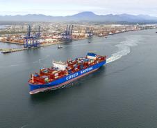 #praquemnaopodever imagem aérea de navio cruzando a Baía de Paranaguá com o Porto de Paranaguá ao fundo. O porta-conteineres azul e vermelho deixa um rastro de espuma branca enquando segue em direção ao Canal de Acesso.