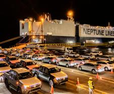 #praquemnaopodever imagem aérea da ponta do cais, onde os carros estacionados aguardam os motoristas para seguirem em direção ao patio. É noite, o navio metade preto e metade azul está com as luzes amarelas acesas.