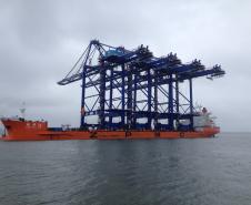 Atracou na tarde desta sexta-feira (23), no Porto de Paranaguá, o navio que trouxe os quatro portêineres de última geração que serão instalados no novo cais de atracação do Terminal de Contêineres. As estruturas vieram montadas e prontas para o uso, medindo cerca de 75 metros de altura. 