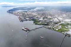 #praquemnaopodever em meio a Baía de Paranaguá, está um píer com dois navios atracados. Ao fundo, várias casas e empresas que foram a área portuária. As nuvens cobrem a cidade