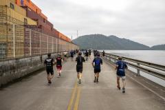 #praquemnaopodever vários corredores aparecem de costas cruzando o cais, pelas margens do Porto de Paranaguá. À direita, aparecem as aguas da baía de Paranaguá, ao fundo as ilhas cobertas de árvores e à esquerda os contêineres amarelos, vermelhos e laranjas.