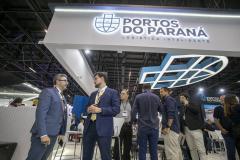dois homens cnversam em frente ao estande da Intermodal no evento. Ao fundo pessoas circulam plo estande.