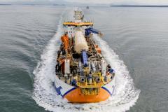 #ParaQuemNaoPodeVer Imagem aérea de um navio em movimento no mar. O navio está cortando a água, criando uma esteira branca ao seu redor. A embarcação possui várias estruturas e equipamentos coloridos em sua parte superior, incluindo elementos em azul, laranja e amarelo.