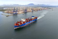 #praquemnaopodever imagem aérea de navio cruzando a Baía de Paranaguá com o Porto de Paranaguá ao fundo. O porta-conteineres azul e vermelho deixa um rastro de espuma branca enquando segue em direção ao Canal de Acesso.