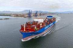 #praquemnaopodever foto aérea mostra navio metade vermelho metade azul, lotado de contêineres cruzando a Baía de Paranaguá deixando uma esteira de espuma, com o cais do Porto de Paranaguá ao fundo.