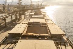 #praquemnaopodever imagem aérea de um navio no fim de tarde, no contraluz, em tom marrom e repleto de carga de milho em um dos porões.