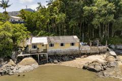 #praquemnaopodever imagem aérea da casa amarela as margens da baía de paranagua. Ao fundo, as arvores e casas dos moradores da Ilha de Eufrasina