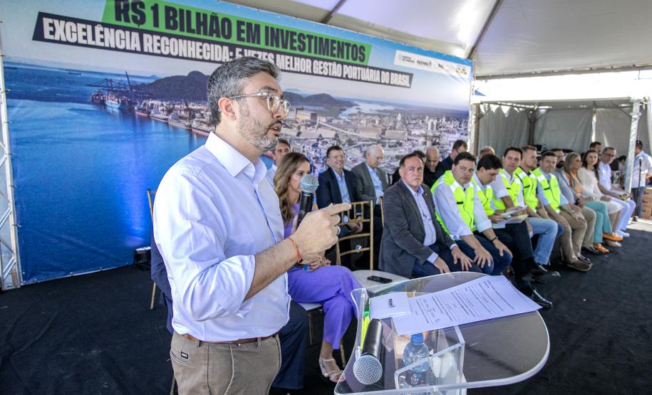 #praquemnaopodever homem de camisa branca de manga está no palco gesticulando com um microfone na mão esquerda. De fundo, várias pessoas estão sentadas olhando a plateia e acompanhando o discurso embaixo de uma tenda