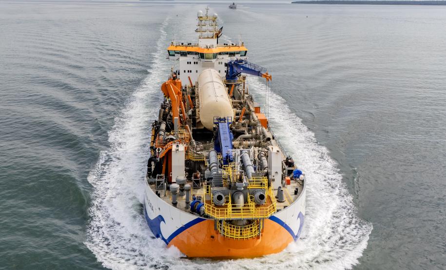 #ParaQuemNaoPodeVer Imagem aérea de um navio em movimento no mar. O navio está cortando a água, criando uma esteira branca ao seu redor. A embarcação possui várias estruturas e equipamentos coloridos em sua parte superior, incluindo elementos em azul, laranja e amarelo.