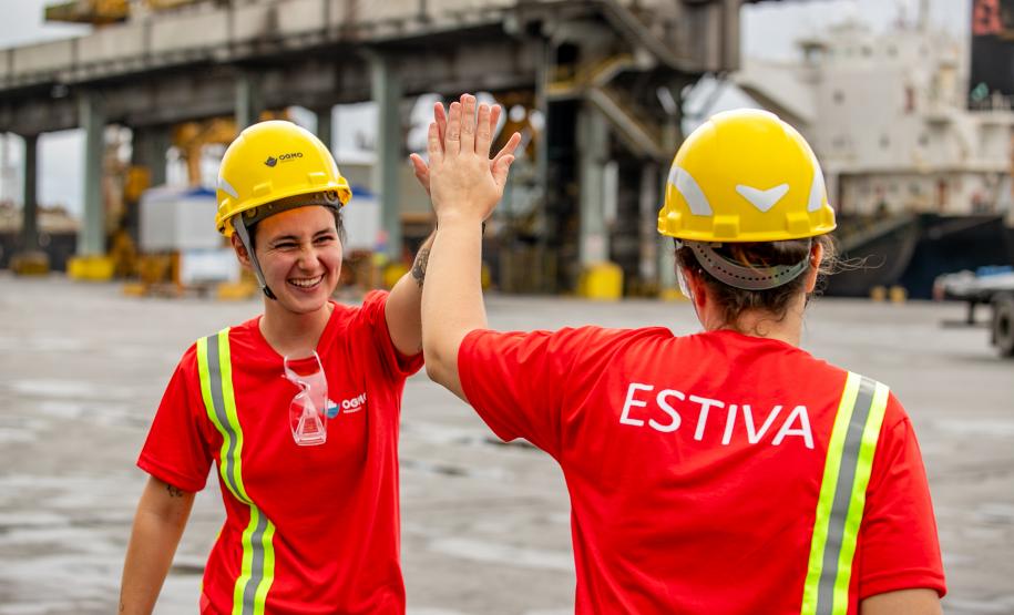 #praquemnaopodever na foto, uma mulher esta rindo de frente e batendo na mão da irmá, que está de costas para a câmera. As duas estão equipadas com capacete e vestem uma camisa vermelha com a palavra "Estiva"