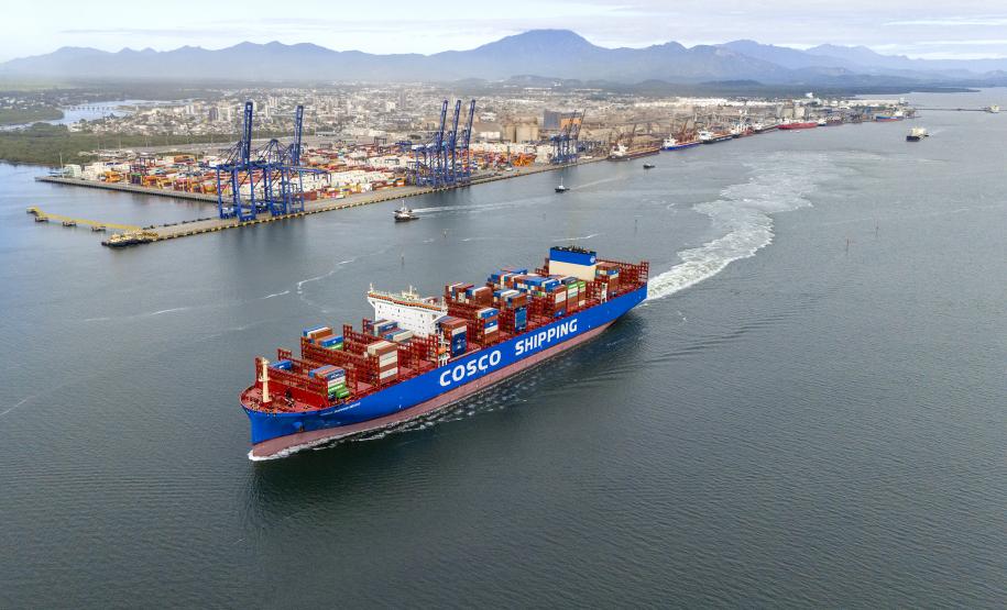 #praquemnaopodever imagem aérea de navio cruzando a Baía de Paranaguá com o Porto de Paranaguá ao fundo. O porta-conteineres azul e vermelho deixa um rastro de espuma branca enquando segue em direção ao Canal de Acesso.