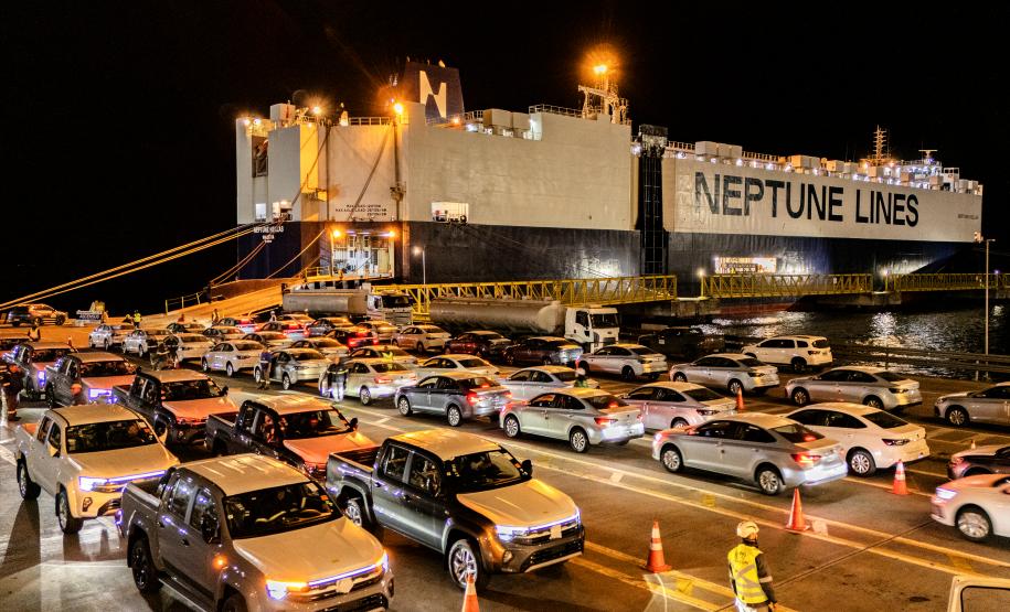#praquemnaopodever imagem aérea da ponta do cais, onde os carros estacionados aguardam os motoristas para seguirem em direção ao patio. É noite, o navio metade preto e metade azul está com as luzes amarelas acesas.
