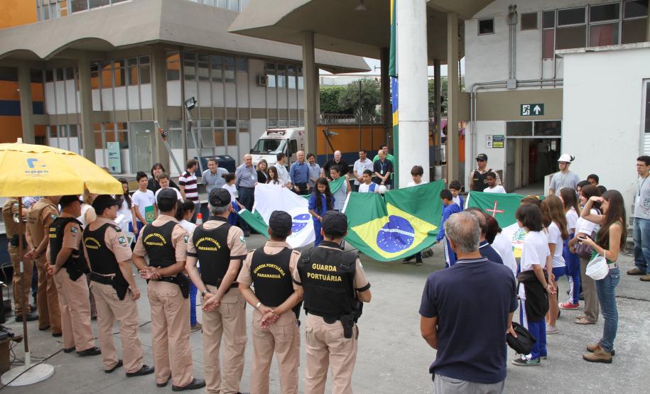Nesta quarta-feira (19), os alunos do sexto ano da Escola Estadual Faria Sobrinho, de Paranaguá, e os trabalhadores da Administração dos Portos de Paranaguá e Antonina (Appa) fizeram, juntos, a cerimônia da troca da flâmula do portão principal do Porto de Paranaguá. O ato cívico, com participação da Polícia Militar do Paraná, marcou o Dia da Bandeira.